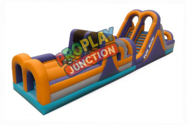 Inflatable obstacle course in orange and purple with archways, climbing wall and dual slide